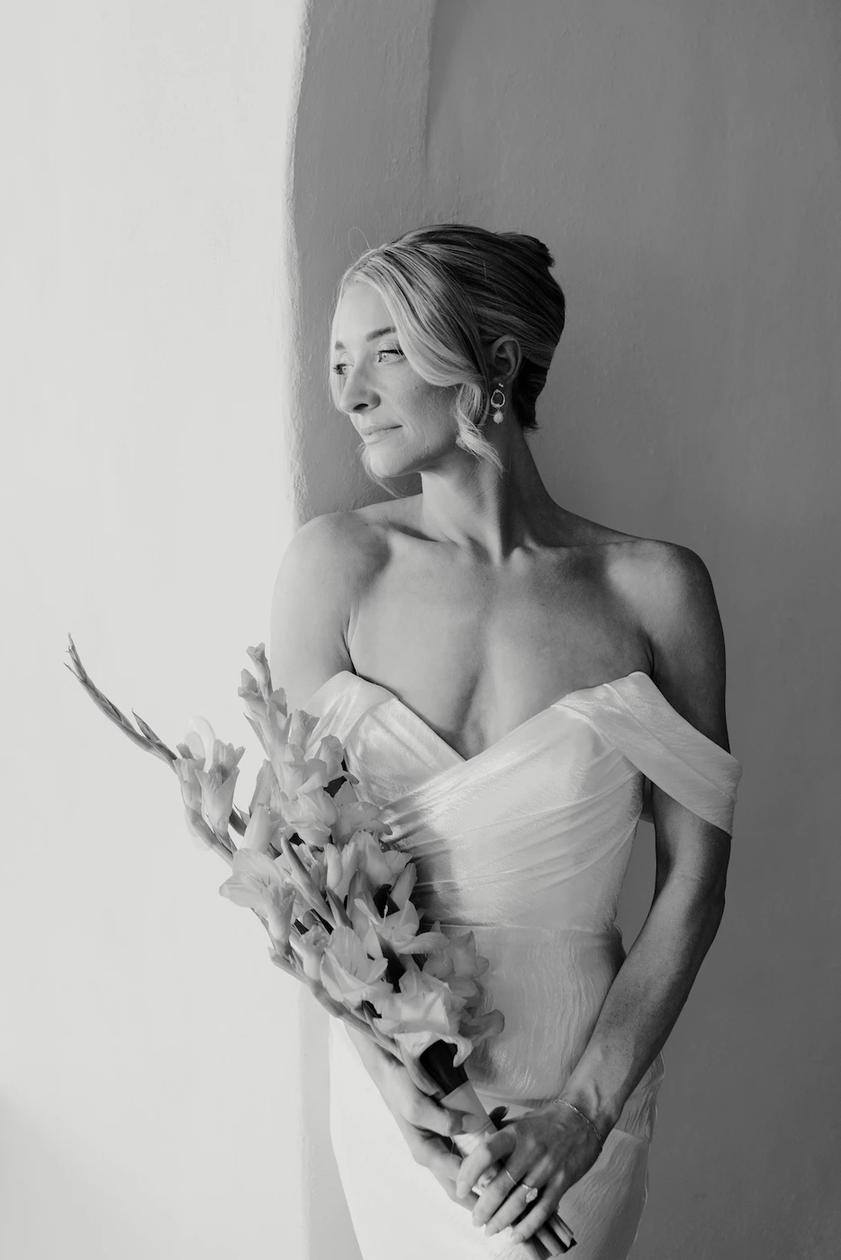 Black and white bride portrait with bouquet leaning against white wall Puerto Vallarta wedding photography