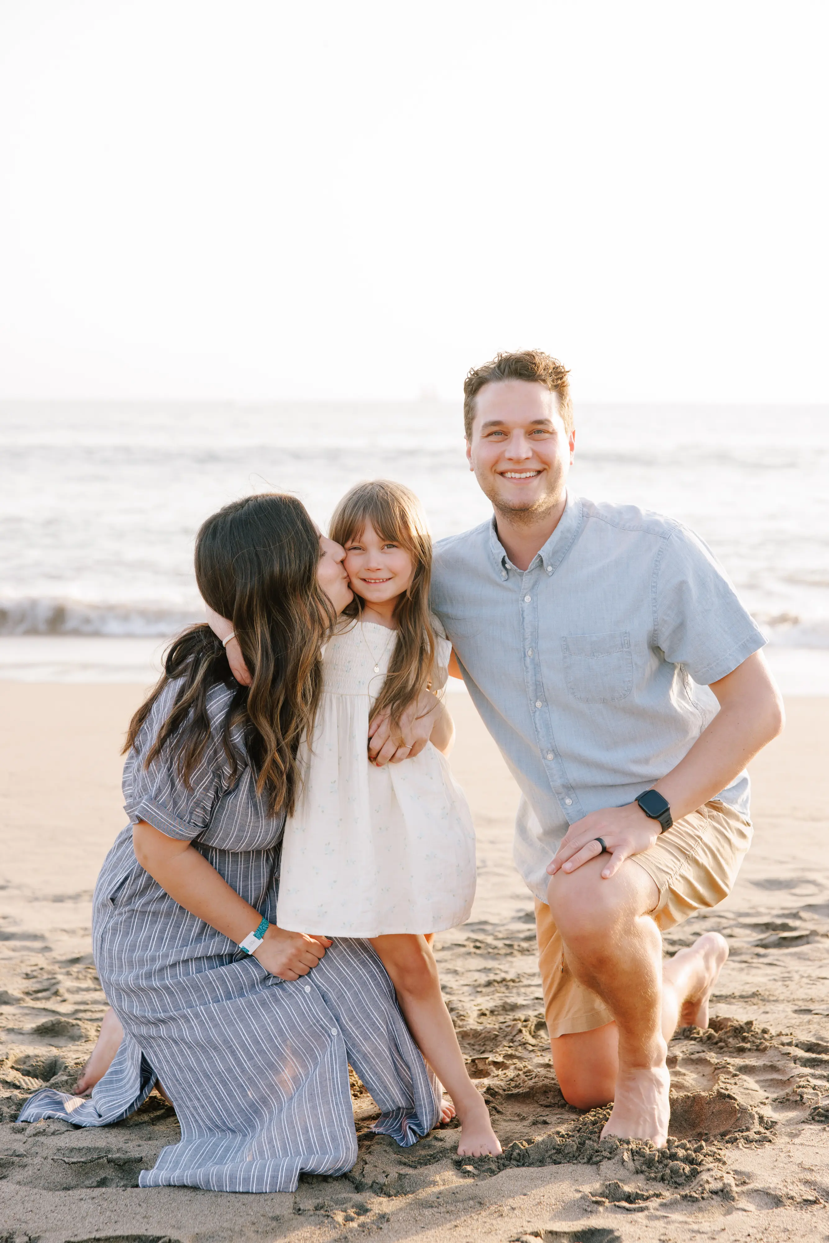 Mother kissing daughter on cheek during candid family photo session in Puerto Vallarta