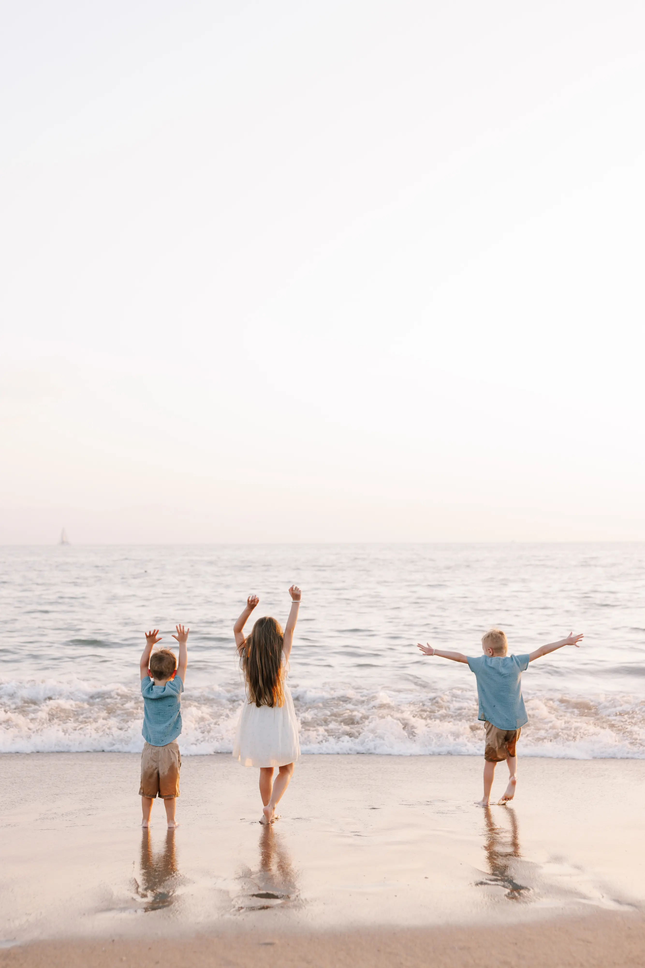 Three children with arms raised celebrating at sunset on Puerto Vallarta beach