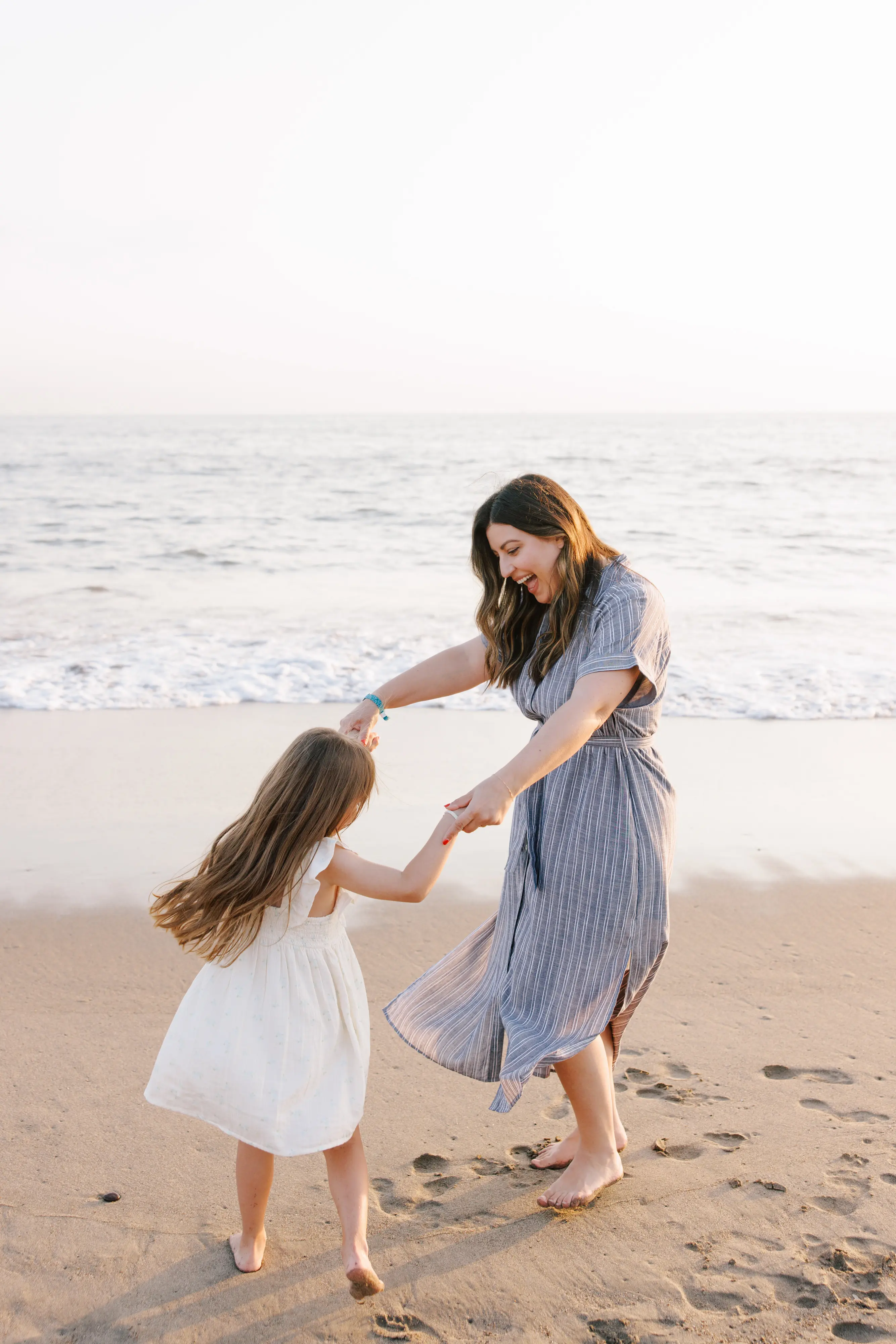 Mother spinning daughter on the beach during family session in Puerto Vallarta