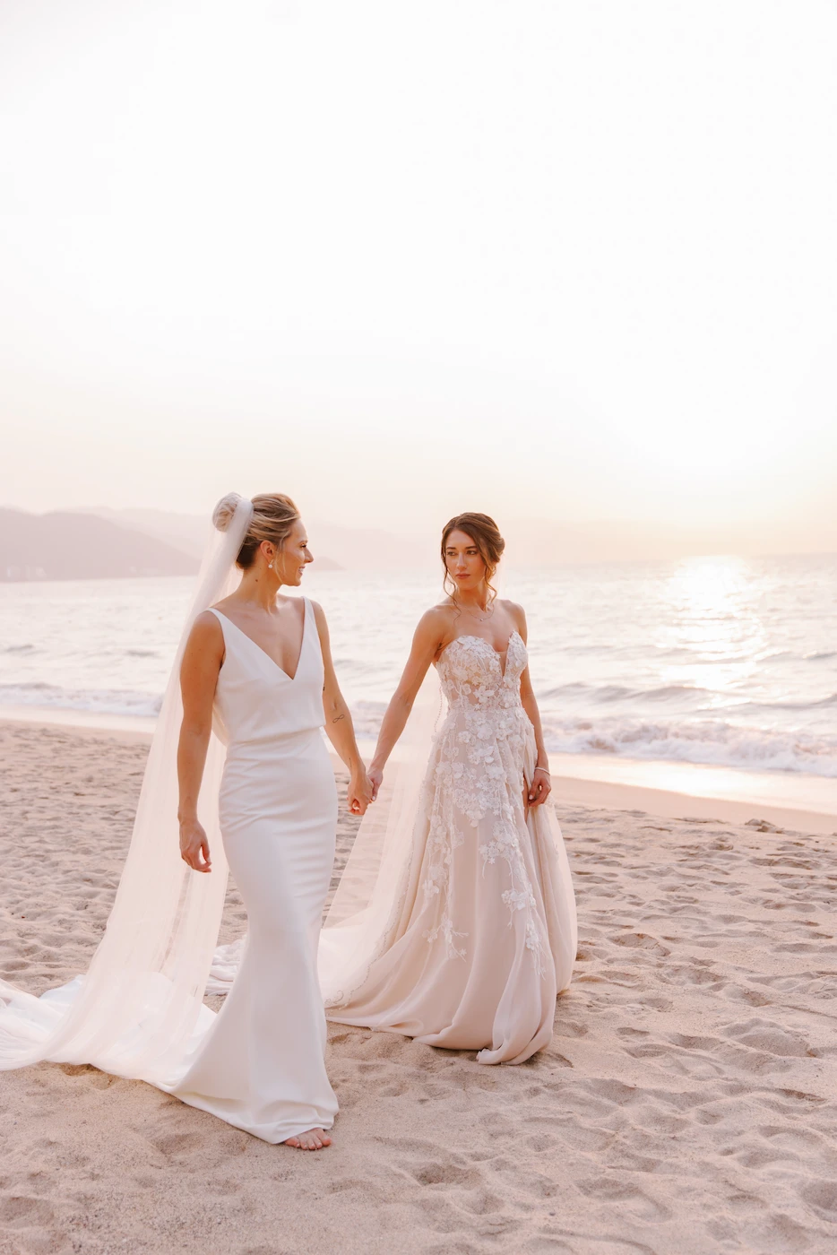 Two brides holding hands walking on the beach at sunset Puerto Vallarta wedding photographer