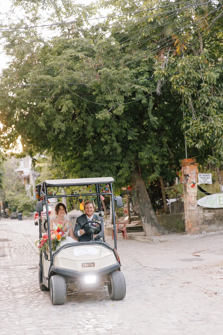 Wedding couple riding through Sayulita cobblestone streets by photographer Evgenia Kostiaeva