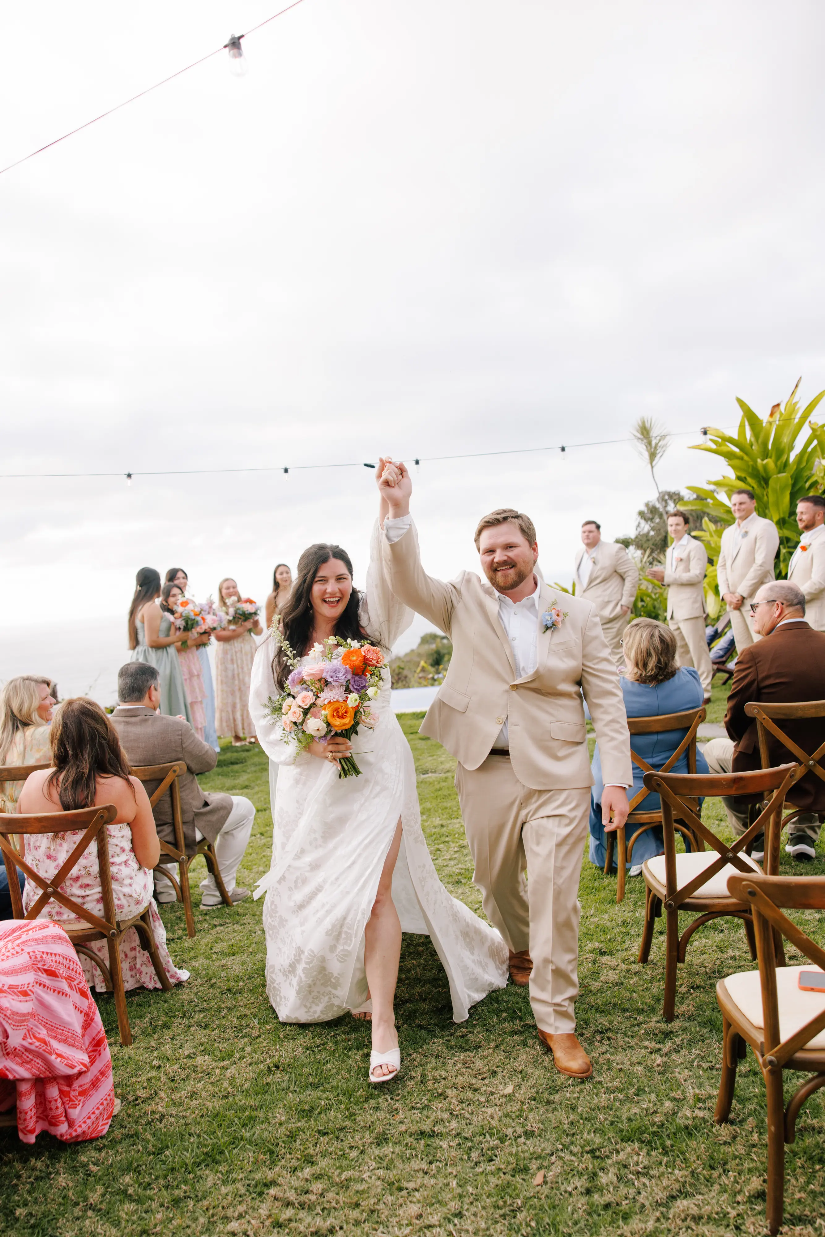 Bride and groom celebrating as they walk down the aisle at an outdoor wedding in Sayulita Mexico photographed by Evgenia Kostiaeva